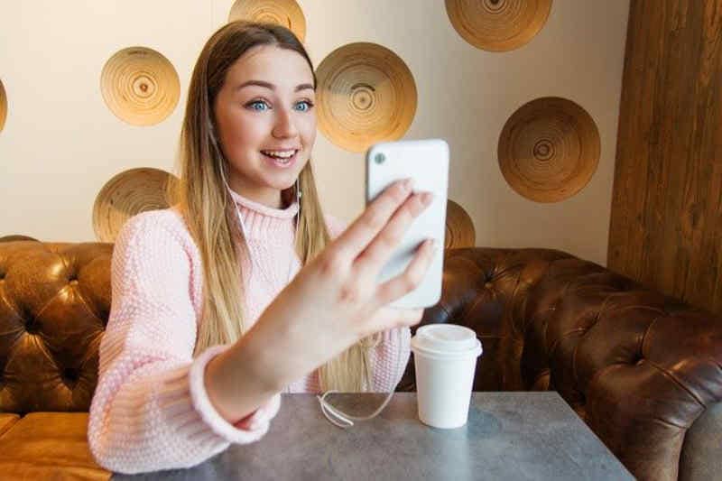 Young woman recording a video with a phone.